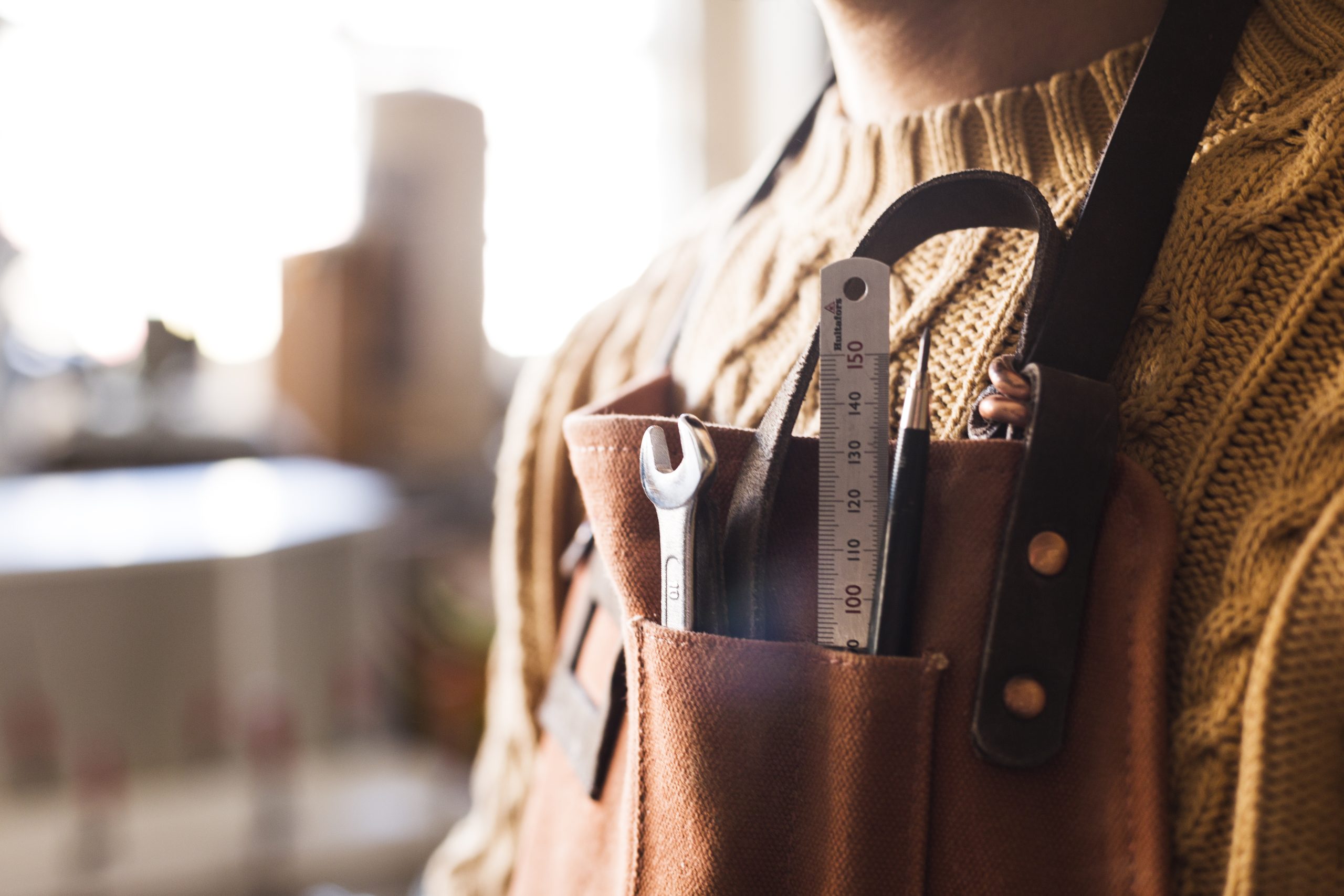 Midsection of carpenter with work tools in apron pocket at workshop